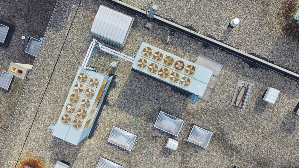 Vue aérienne des unités de CVC commerciales et des équipements de ventilation installés sur un toit plat recouvert de gravier.