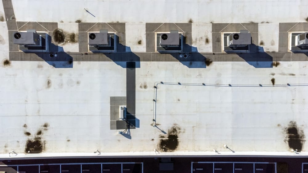 Vue de dessus d'avion d'un toit plat d'un bâtiment industriel avec des unités HVAC. Pondre les points d'eau sales.