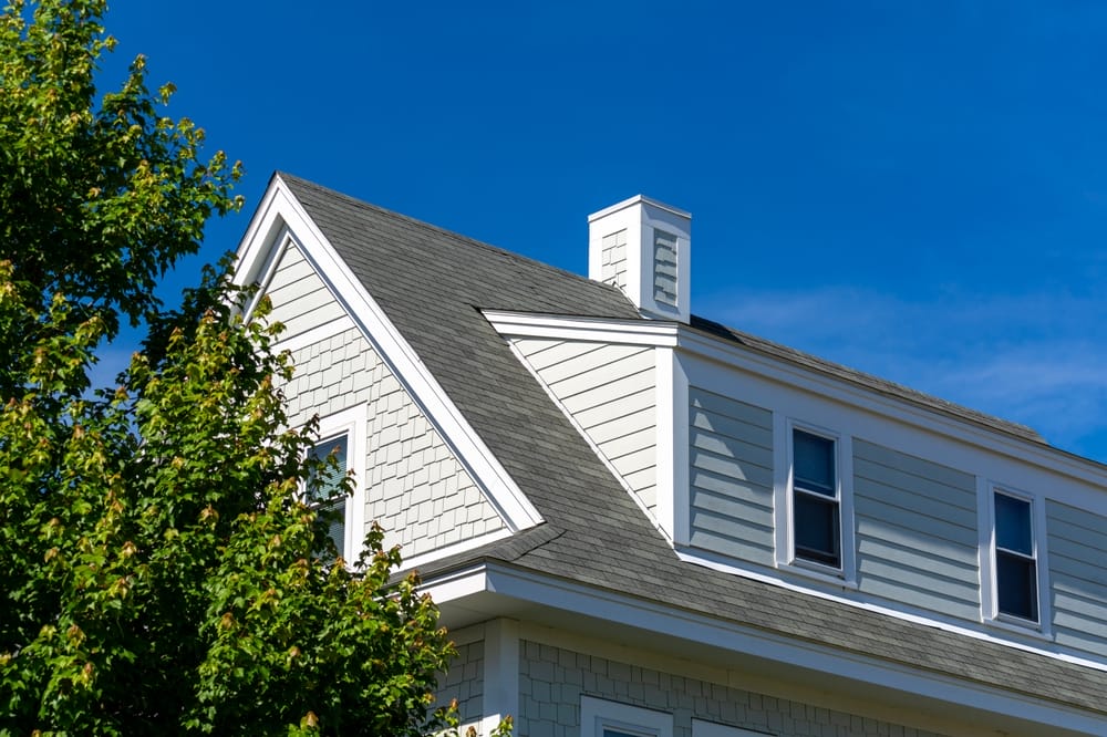 Partie supérieure d’une maison neuve avec lucarne en appentis sous un ciel bleu clair