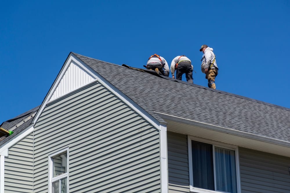 Des couvreurs professionnels effectuent l’entretien d’une maison à toit à pignon