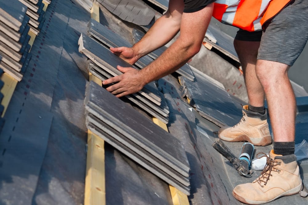 Travaux de toiture en cours avec la pose d’un nouveau revêtement de tuiles réalisé par un couvreur.