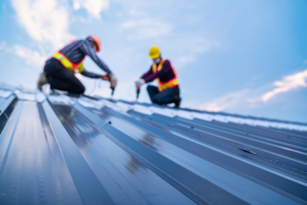 Selective focus roof, construction worker safety wear using electric drill tools install on new roof metal sheet, Roof construction concept.